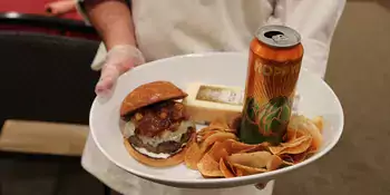 Chef holding white plate with hamburger and chips