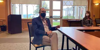 Man sitting at table wearing mask and orange checkerboard socks