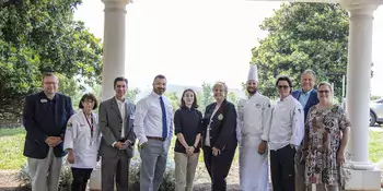 10 men and women standing outside under a portico