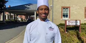Young man in chef's uniform standing outside a building