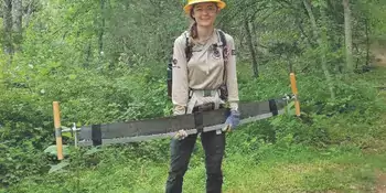 Young woman holding tree saw in a forest