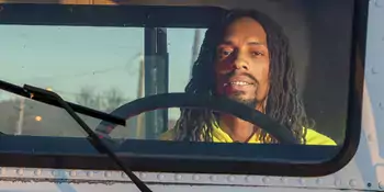 Man wearing yellow shirt sitting in the cab of a truck