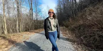 Woman in jacket and hat standing on a trail