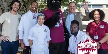 A group of students with Dr. Gossett and Trailblazer bear on a deck