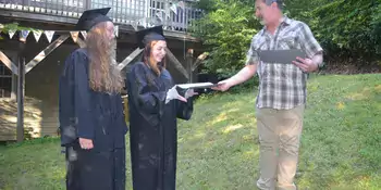 HIGH SCHOOL HANDOFF: Claire Bowling, left, and Amelia Darnell receive their high school diplomas in July 2019 from Chuck Bowling, who served as principal of their home school, Parkview Academy. Photo by Roger Darnell