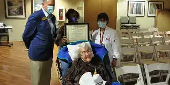 A woman in a wheelchair with 3 people standing behind her. 