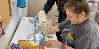 Woman at sewing machine with instructor leaning over