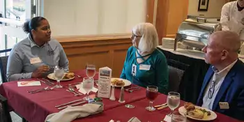 Student eating lunch with two donors 