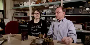 woman and man sitting at a table with an old radio in front of them