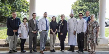 10 men and women standing outside under a portico