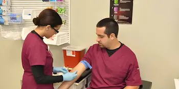 Woman drawing blood from the arm of a man