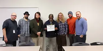 Heath Moody and his students in the Issues In Sustainability class against a wall with a certificate.