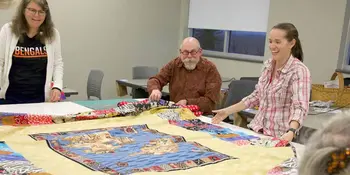 Three people at a table with a quilt