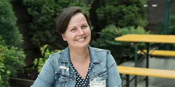 Woman sitting at a picnic table with a beer
