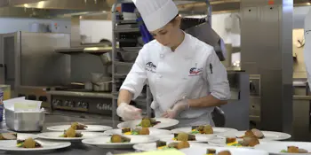 Student chef preparing plates of food.