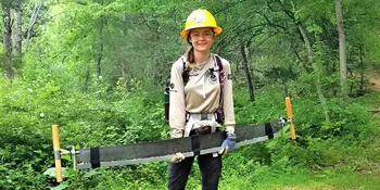 Young woman holding tree saw in a forest