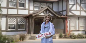 Anne Rasheed in front of a house holding a sold sign