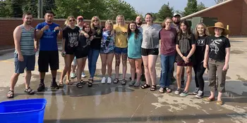 A group of wet students standing on a concrete surface. 
