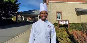 Young man in chef's uniform standing outside a building